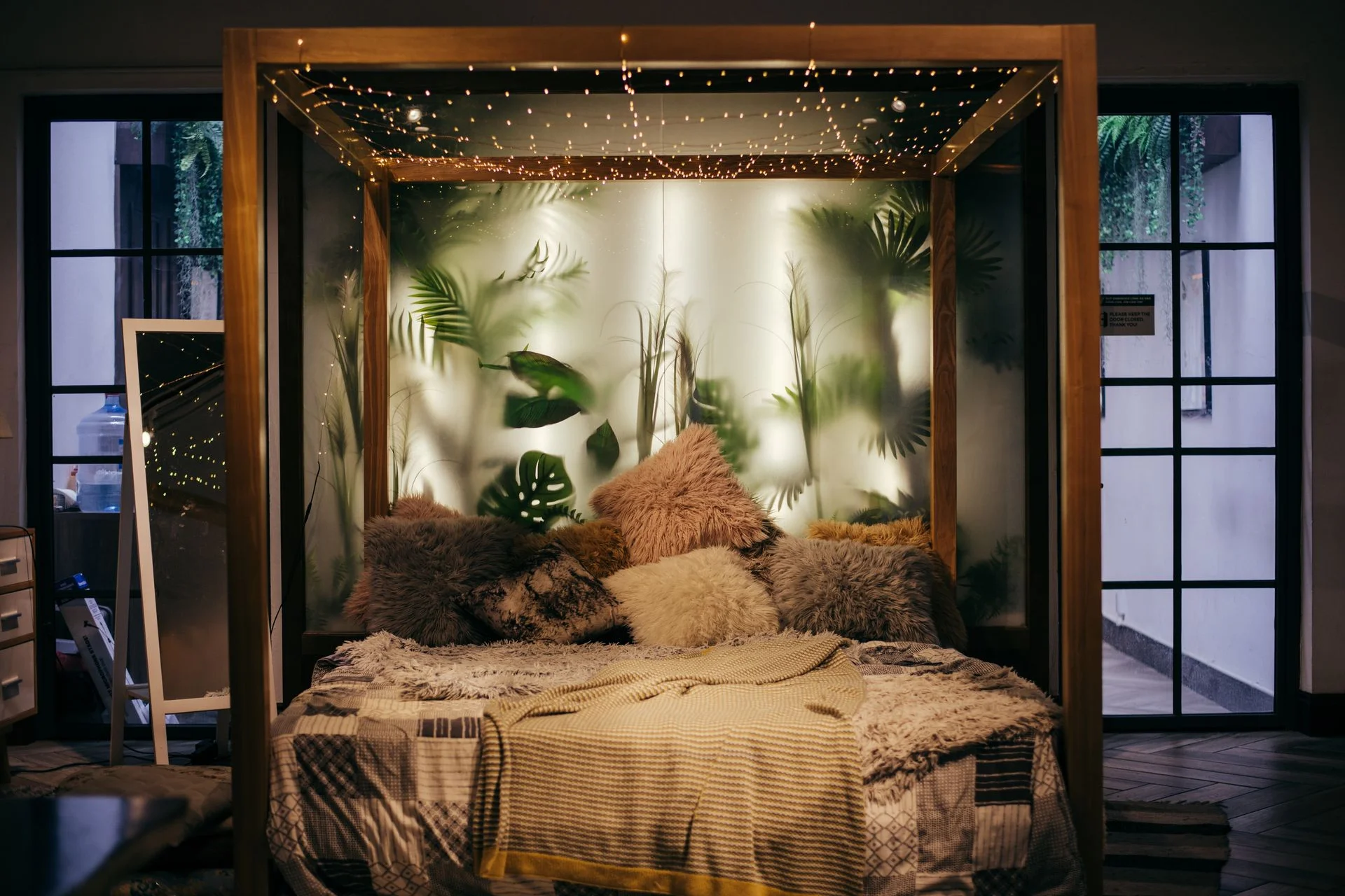 A cozy bedroom with string lights on the bed frame and plants
