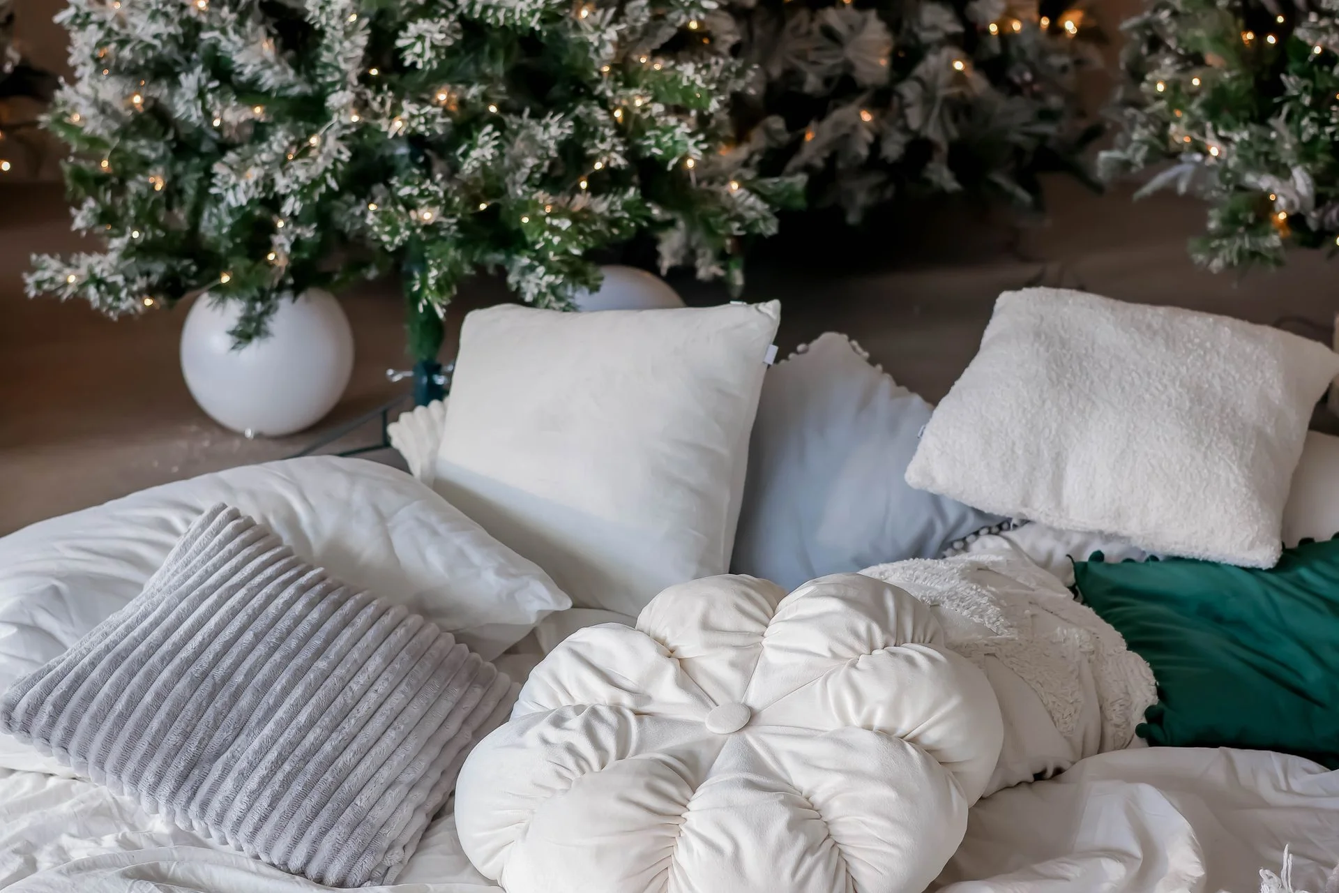 A cozy winter bedroom scene with christmas trees, warm lights, and soft pillows