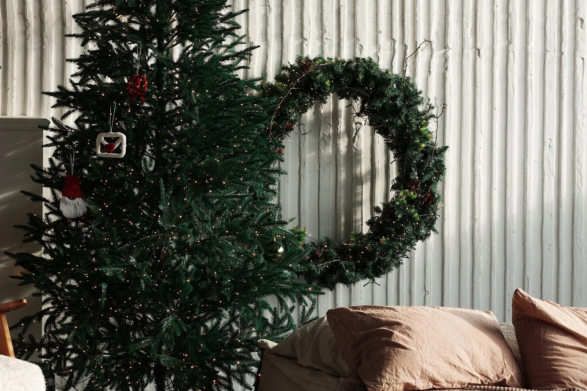 A cozy bedroom decorated with a christmas tree and a pine wreath