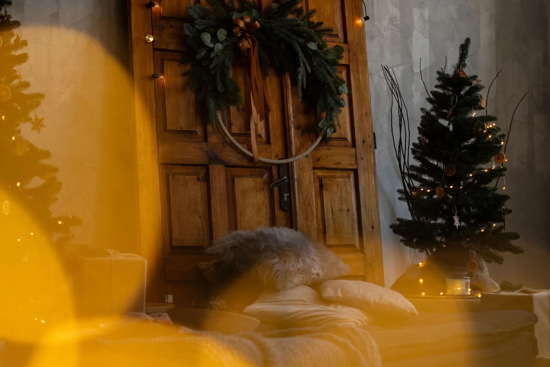 A warm christmas setting with a decorated wooden door and festive lights